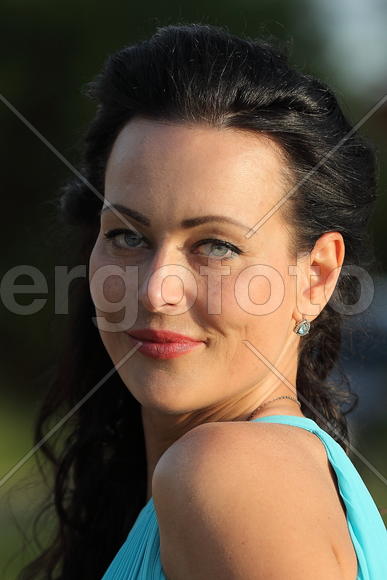 Портрет брюнетки в голубом платье крупным планом.