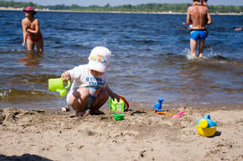 Мальчик играет с лейкой на берегу реки 