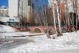 Арочный пешеходный мост из кирпича через речку в московском парке