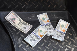Несколько купюр американских долларов лежат на коврике в машине
