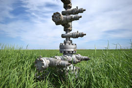 Canned oil well against the sky and field. Equipment of an oil well. Shutoff valves and service