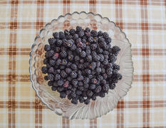 Тарелка с ягодами черной ежевики. Фрукты ягоды на столе.