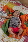 Indian baby lying on colorful mat in the village