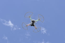 Drone with a video camera flying in the blue sky