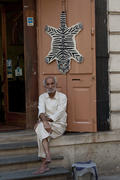 An older man sitting at the entrance to his shop in Mumbai
