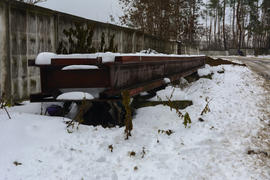 Большой стальной рельс, лежащий возле дороги в зимнее время