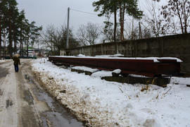 Большой стальной рельс, лежащий возле дороги в зимнее время