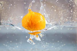 желтый апельсин падает в воду
