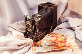 Старинный фотоаппарат и денежные купюры на ткани