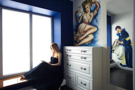 Девушка в синем платье сидит у окна с книгой